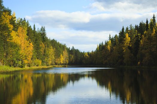 Fall colored forest reflections on the blue water