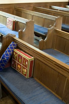 rows of wooden church pews with prayer cushions