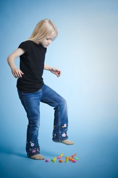 Young girl crushing plastic dinosaurus with her foot