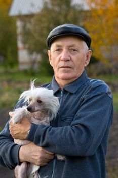 Portrait of the elderly man with a dog of breed chinese crested against the nature