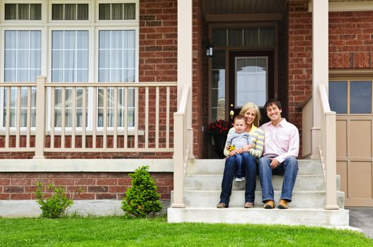 Young family sitting on front steps of house