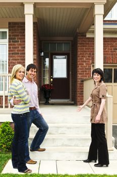 Real estate agent with couple welcoming to new home