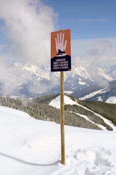 Avalanche warning sign on mountainside in Swiss Alps.
