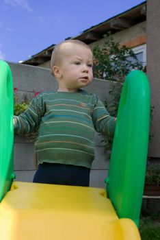 a little boy standing on a plastic shute looking funny