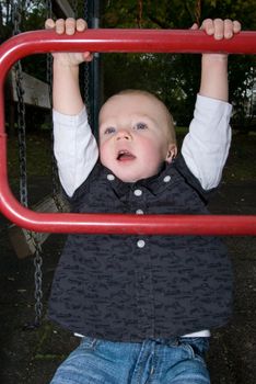 a little boy chinning the bar at the playground