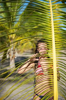 Pretty young woman playing with a palm tree in the Marau Peninsula, Bahia State, Brazil