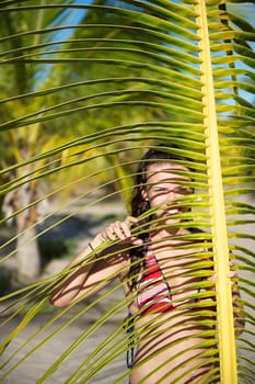 Pretty young woman playing with a palm tree in the Marau Peninsula, Bahia State, Brazil