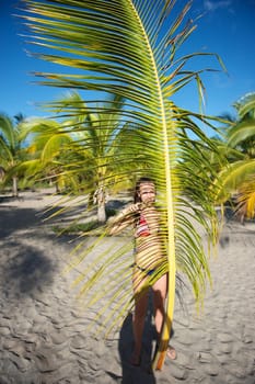 Pretty young woman playing with a palm tree in the Marau Peninsula, Bahia State, Brazil