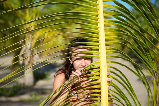 Pretty young woman playing with a palm tree in the Marau Peninsula, Bahia State, Brazil