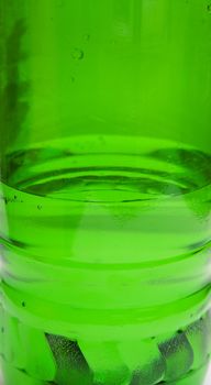 Green plastic bottle with water. A background, macro