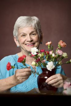 Senior woman at home with colorful flowers