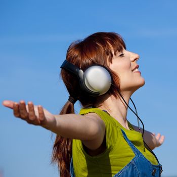 Portrait of a happy woman listen music over a beautiful blue sky