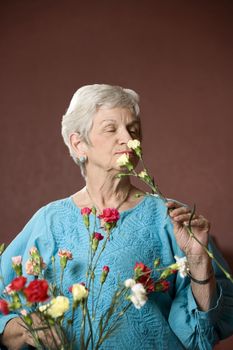 Senior woman at home with colorful flowers