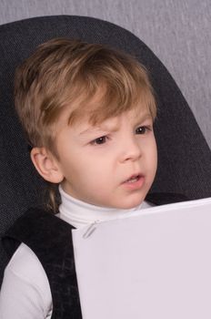 Six years boy reading a book at home