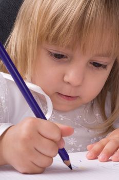 Beautiful little girl is drawing with crayons on paper