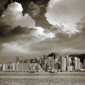 Skyline and Victoria Harbor under white clouds in Hong Kong.