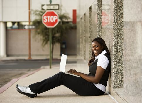 Pretty African American woman on sidealk with laptop computer