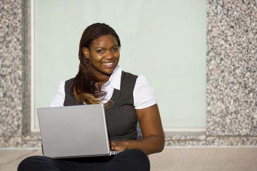 Pretty African American woman on sidealk with laptop computer
