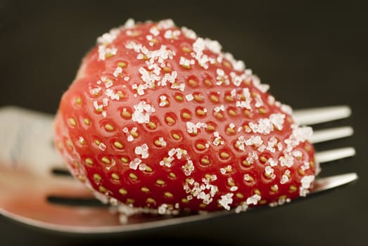 a ripe red strawberry, sprinkled with sugar, ready to eat