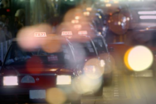 Color night scene of taxi in Hong Kong, focus on 'taxi' words on top of car.