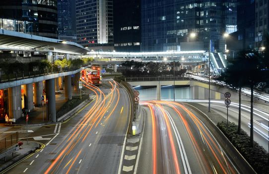 Traffic in city with cars motion blurred light and office building in night.