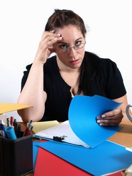 A female office worker looks overworked as she looks through a file.