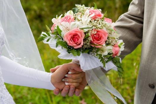 Wedding bouquet in hands of the groom and the bride