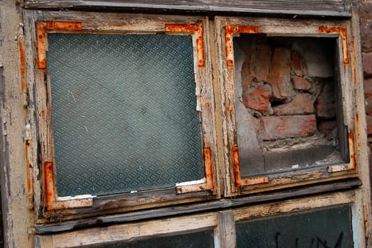 A bricked up window with a chipped paint and rusty frame