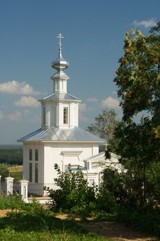 White Christian church on a background of a tree