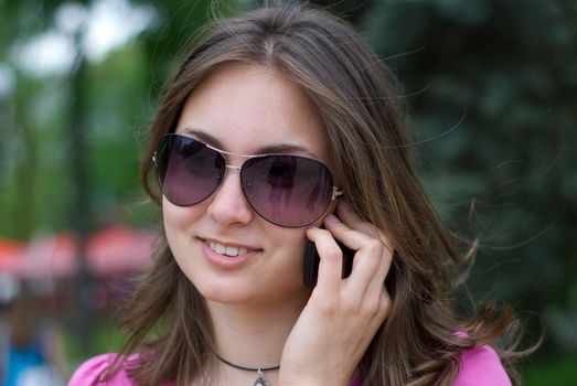 portrait of a beautiful teenage girl in sunglasses with mobile phone