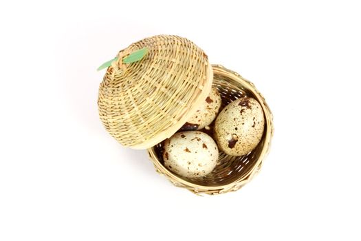 Three eggs of japanese quail in a little basket isolated on white