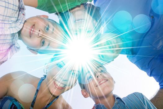 A happy family in a circular huddle formation with a bright lens flare in the center with copy space for your text or image.