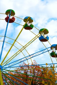 Old big wheel in autumn park against the blue cloudy sky