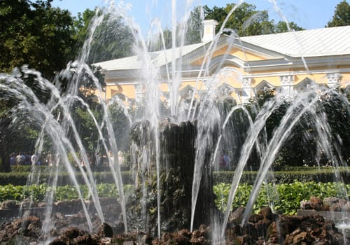 fountain in the park with yellow building
