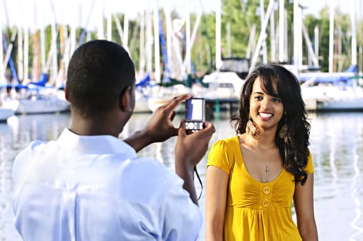 Beautiful woman posing for vacation photo at harbor with sailboats