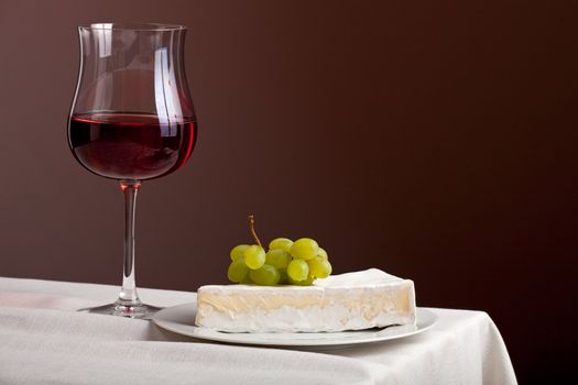 glass of red wine and camembert cheese with grapes