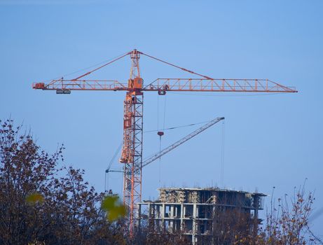 The tower crane on building of the high-rise house against the blue sky
