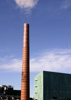 A singular brick steam stack in front of a blue sky