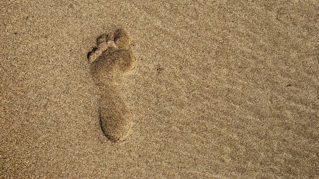 A single footprint in the sand from sraight above