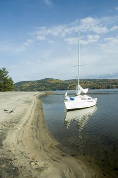 a small white sail boat near the shore