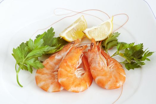 three raw prawns with lemon and parsley on a white plate