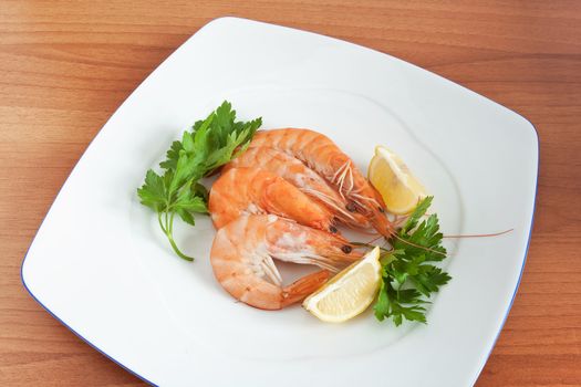 three prepared prawns with lemon and parsley on a white plate