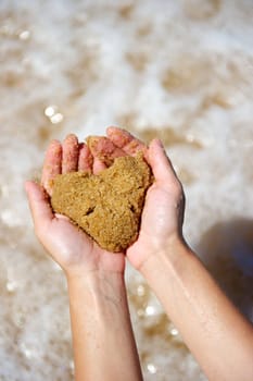 Woman holding an heart in sand in her hands