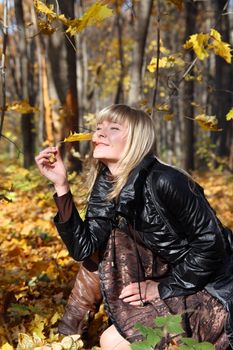 happy young girl with yellow leaf on autumn background