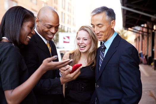 A group of business people looking at a cell phone and laughing