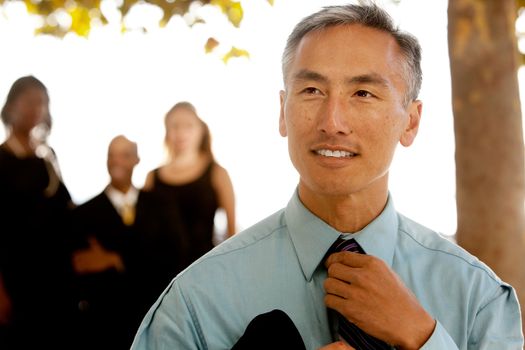 An asian looking business man with colleagues in the background