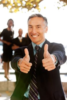 A business man with thumbs up - critical focus on the thumbs