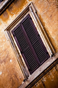 Window on old orange wall in Rome, Italy
