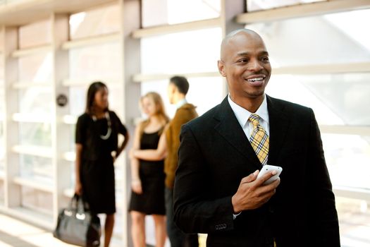 A business man with a smart phone and co-workers in the background