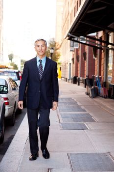 An asian looking business man walking in a street